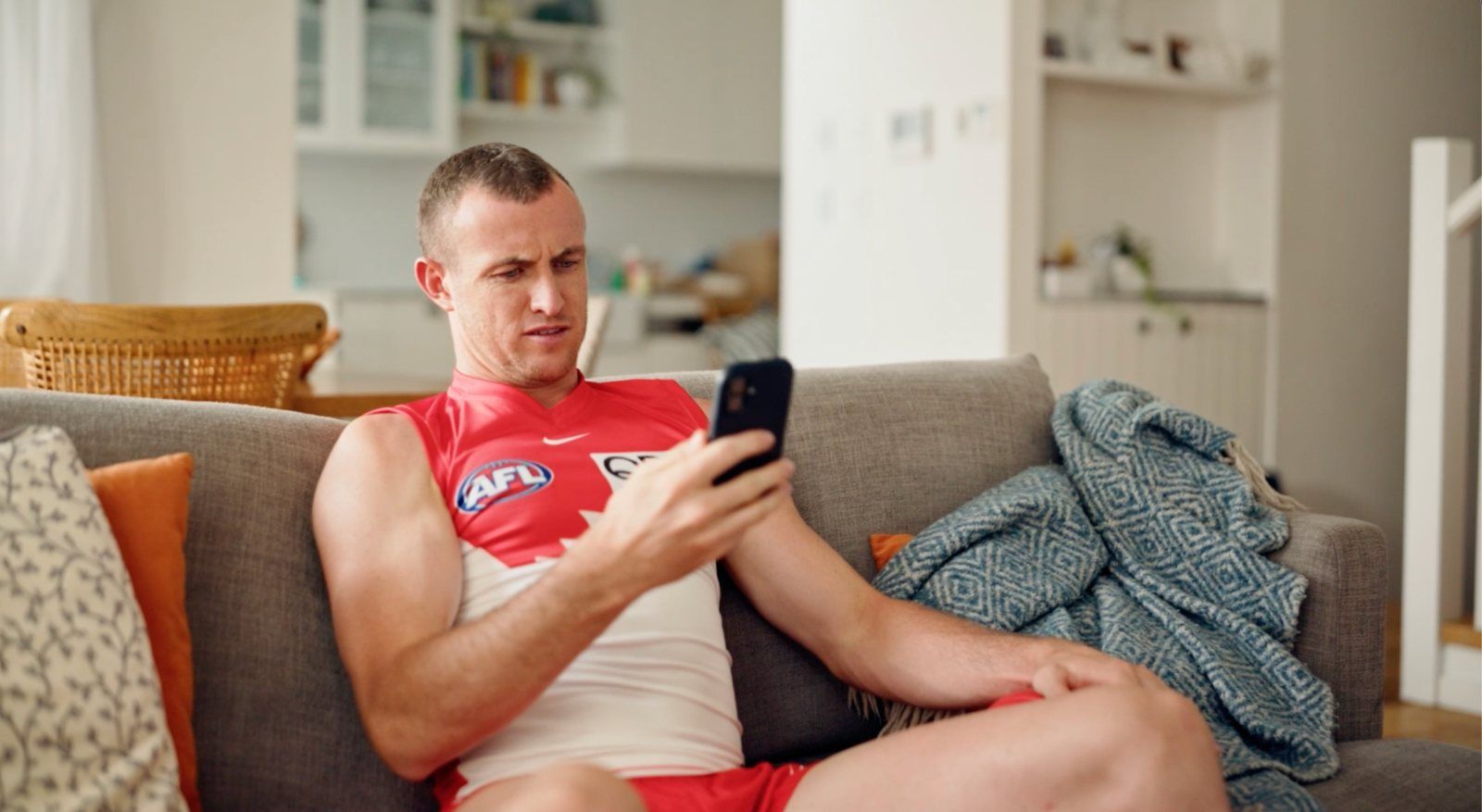 bitcoin.com.au TV spot: an AFL player on the couch frowning at his phone