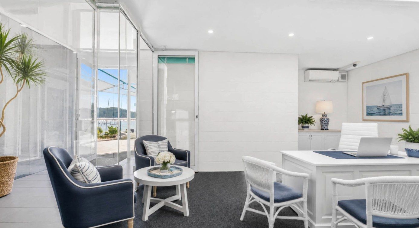 Meeting room with armchairs, a round coffee table and a view through glass doors to the water